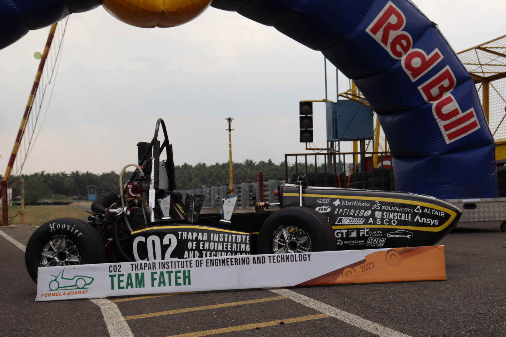 Team Fateh CO2 Formula Student car in side profile under a Red Bull arch at Formula Bharat 2023